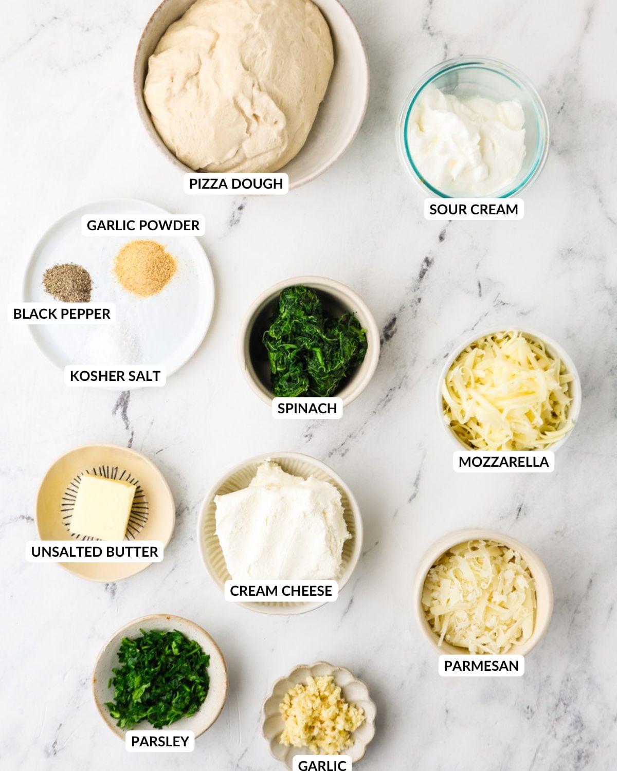 Ingredients for Christmas tree spinach dip breadsticks arranged on a marble surface.