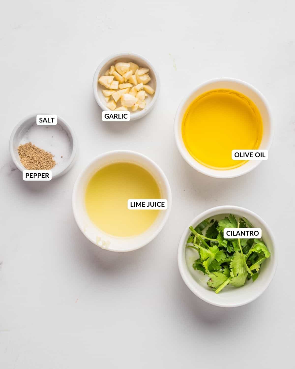 An overhead image of the ingredients of cilantro lime dressing in separate bowls and labeled.