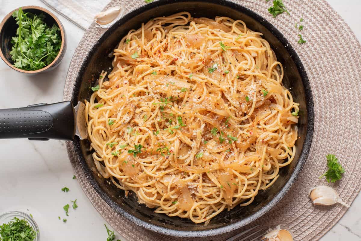 An overhead image of caramelized onion pasta in a. skillet.