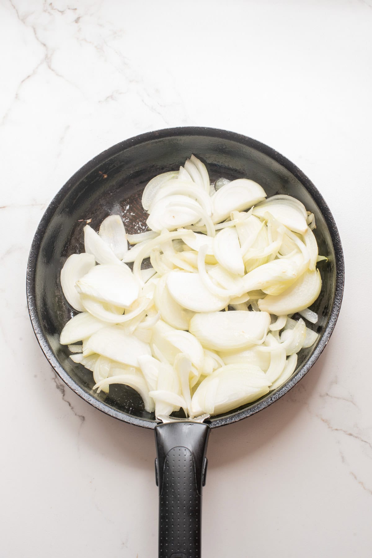 An overhead iamge of adding onions to the skillet.