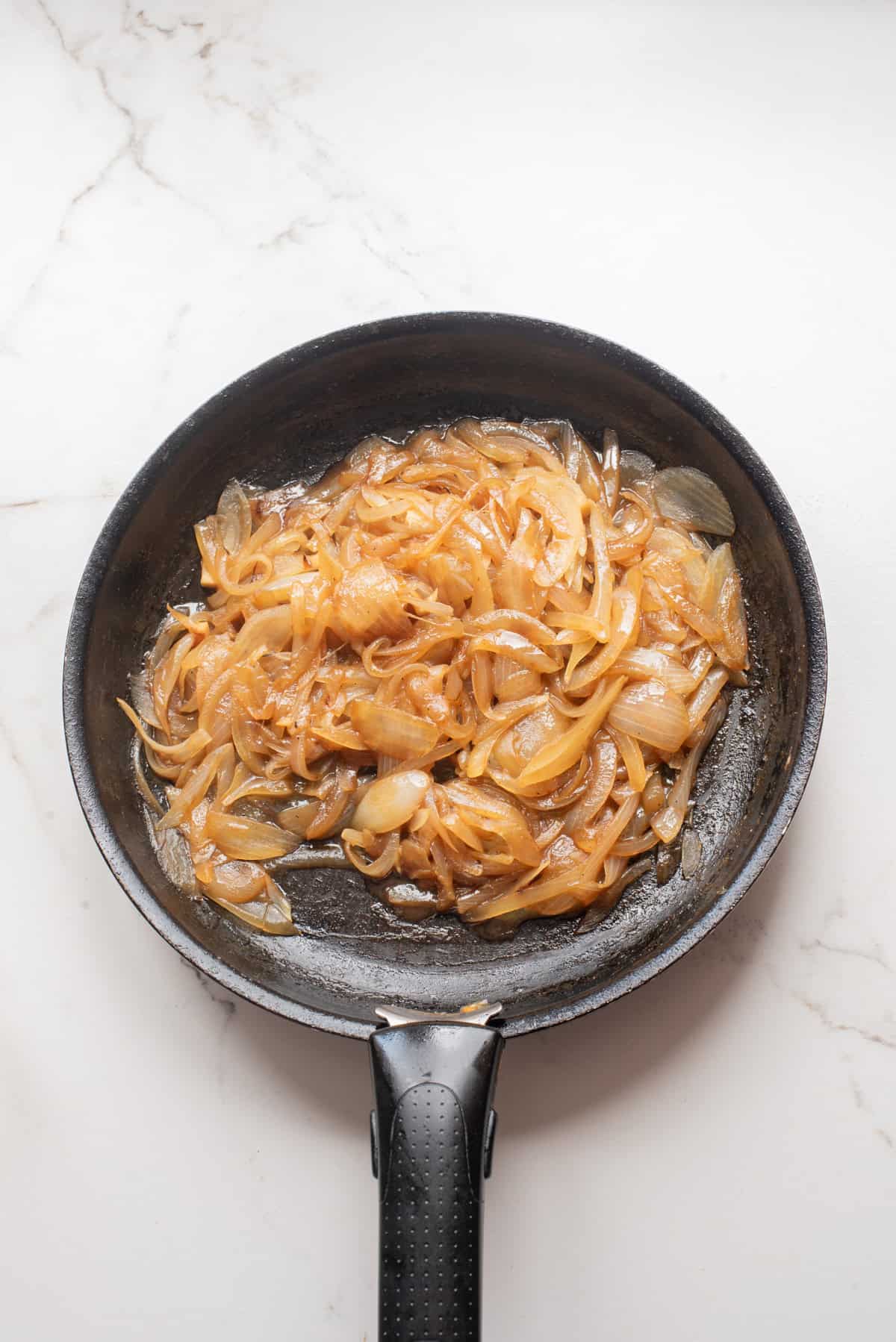 An overhead image of cooking onions in a skillet.