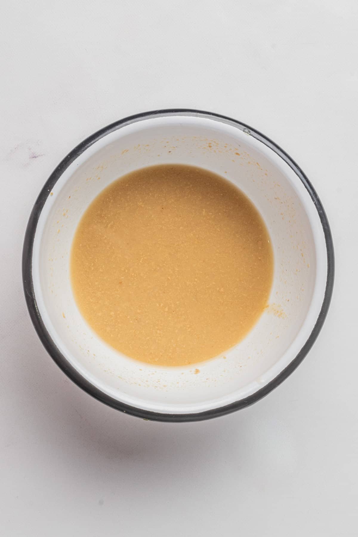 An image of a mixture of champagne vinegar, Dijon mustard, and honey or maple syrup in a small bowl.
