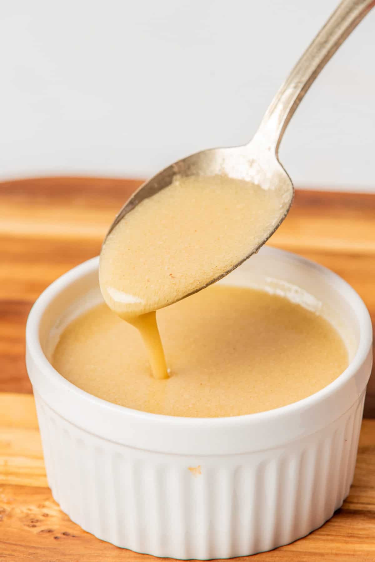 An image of champagne vinaigrette dressing in a ramekin bowl with a spoon.