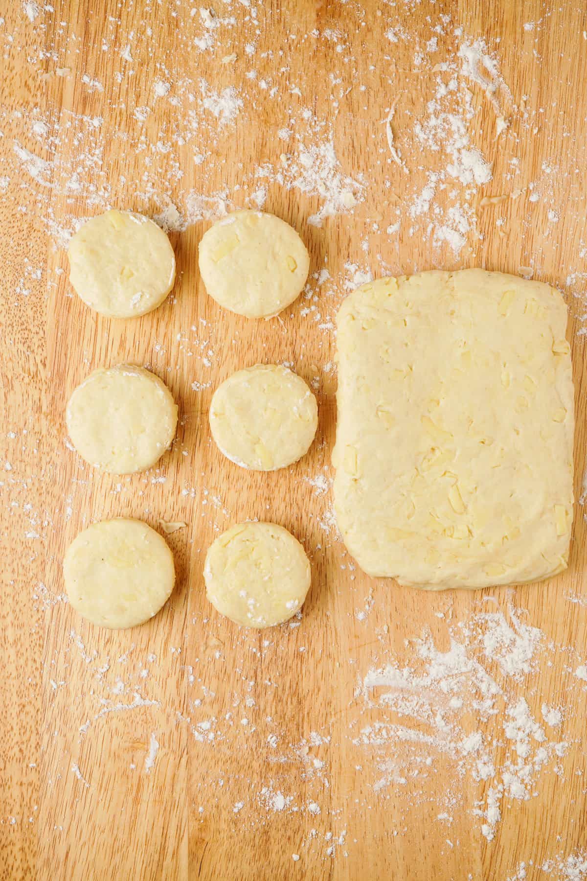 Overhead view showing punched out biscuits next to the layered, flattened dough.