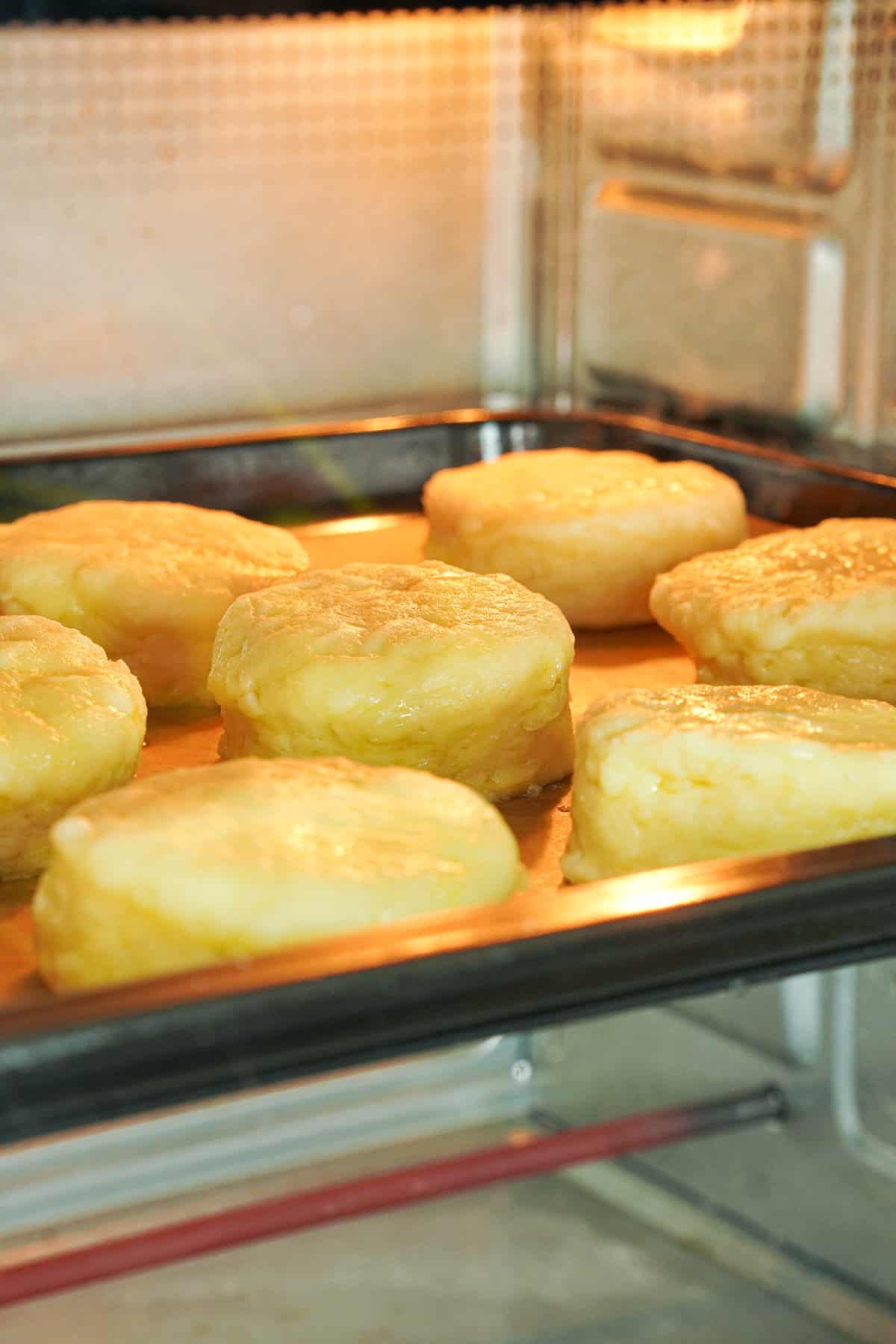Side angle view showing biscuits on cookie sheet inside the oven, baking.