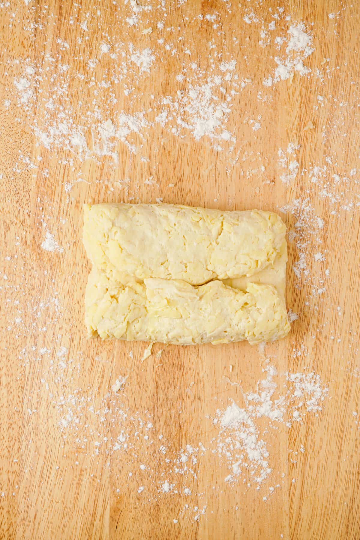 Overhead view showing how to layer biscuits, by folding dough on top of each other like an envelope.