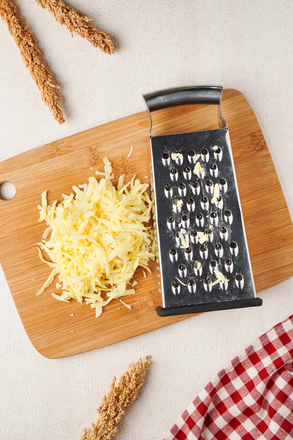 Overhead view showing a box grater and shredded butter on a wooden cutting board.