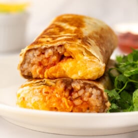 An image of two pieces of bean and rice burrito on a palte.