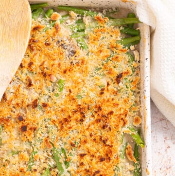 An overhead, close up image of green bean casserole with a golden layer of cheese on top.