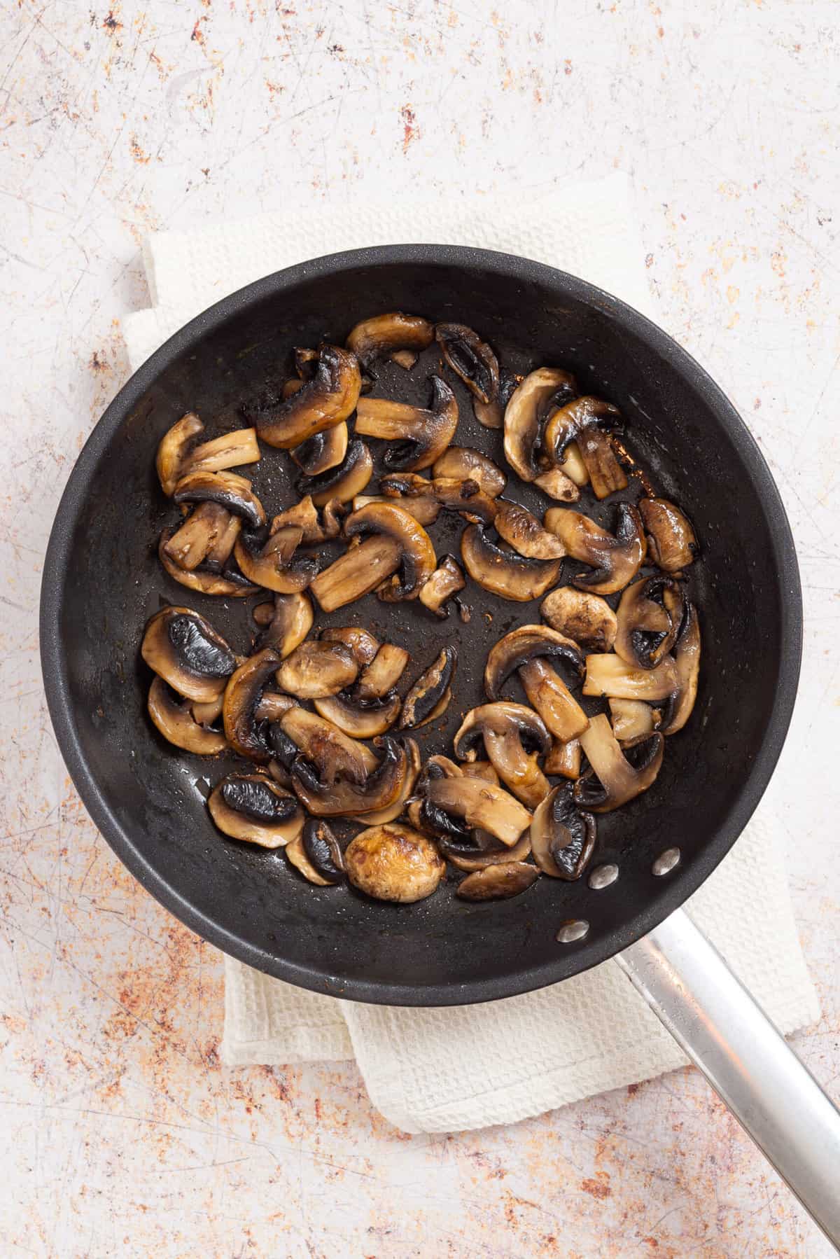 An overhead image of mushrooms cooked on a skillet.