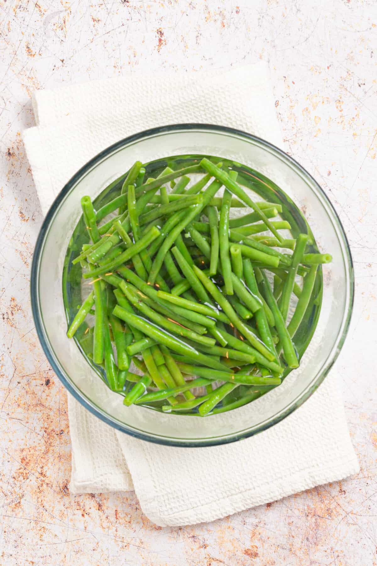 An image of green beans immersed in a bowl of ice cold water.