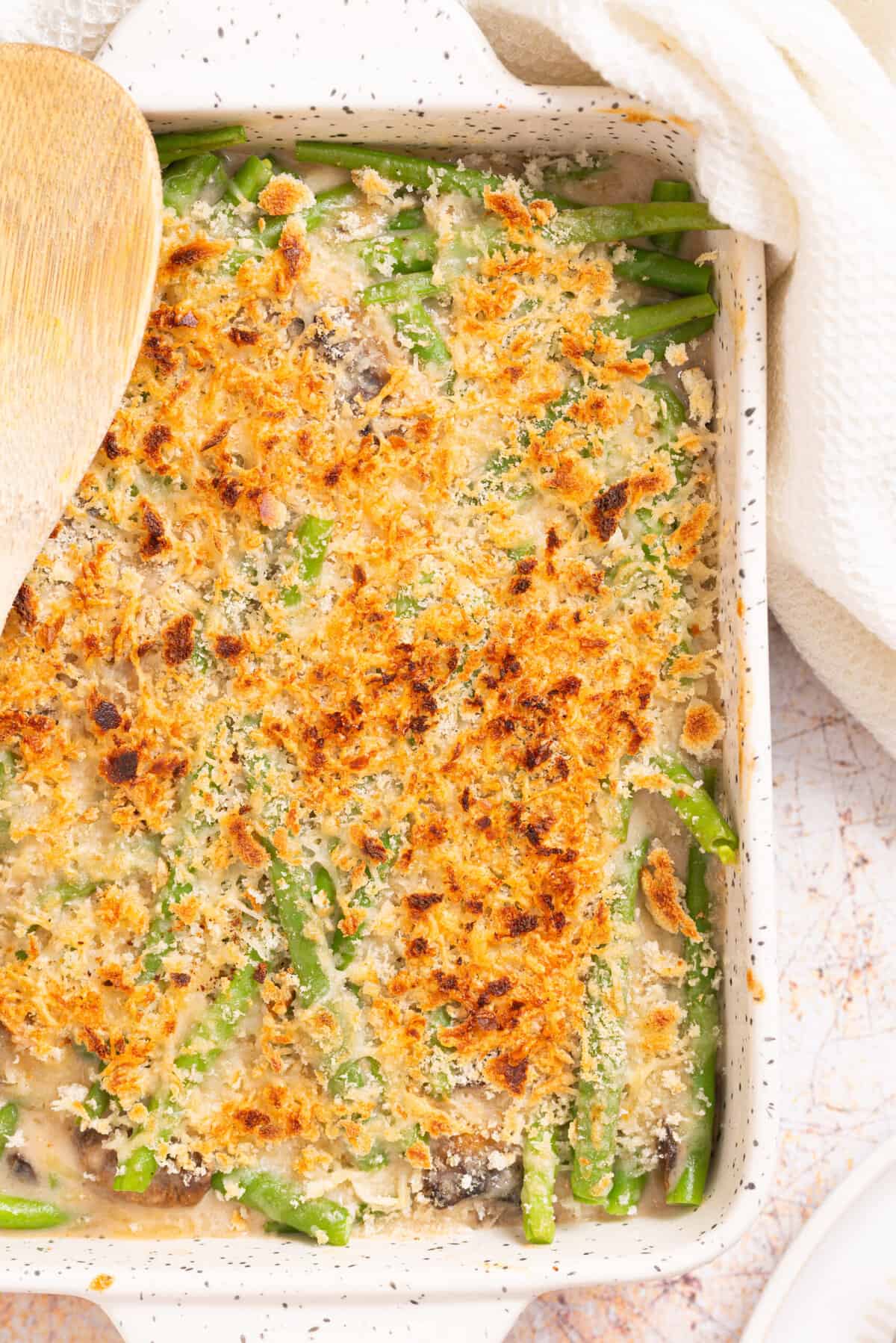 An overhead, close up image of green bean casserole with a golden layer of cheese on top.