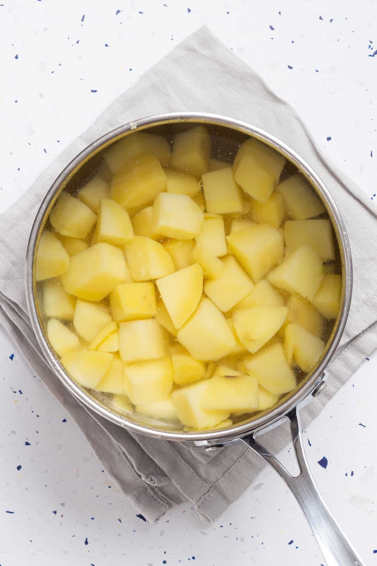 An overhead image of cubed potatoes in a pot.