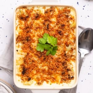 An overhead image of cheesy potatoes in a casserole, garnished with parsley!
