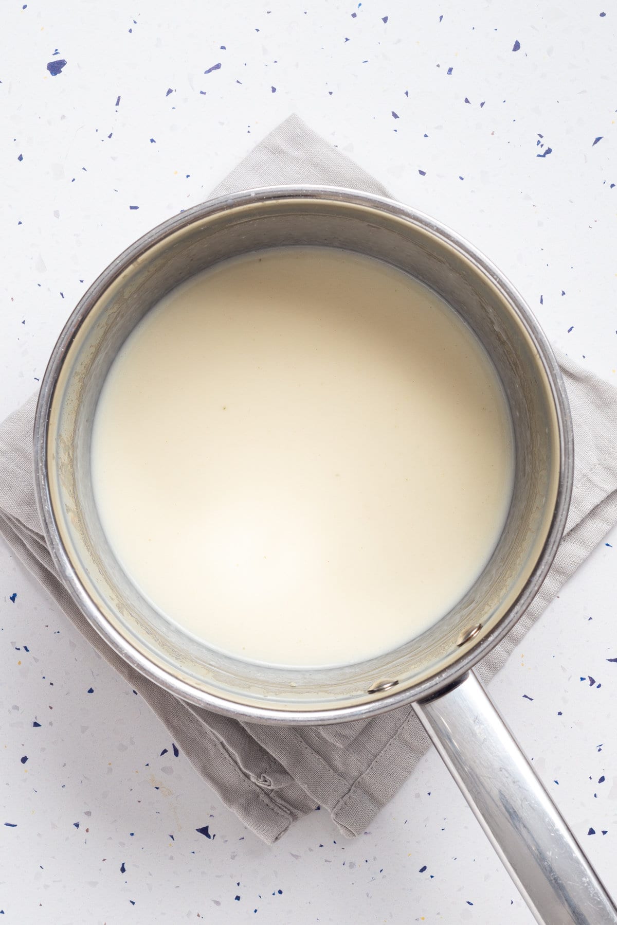 An overhead image of pour the milk and vegetable broth added to a pot.