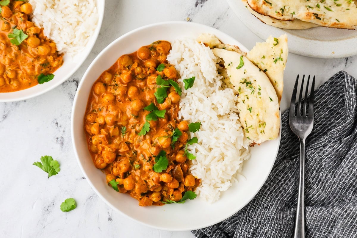 An overhead image of chickpea tikka masala served on a plate with rice and naan.