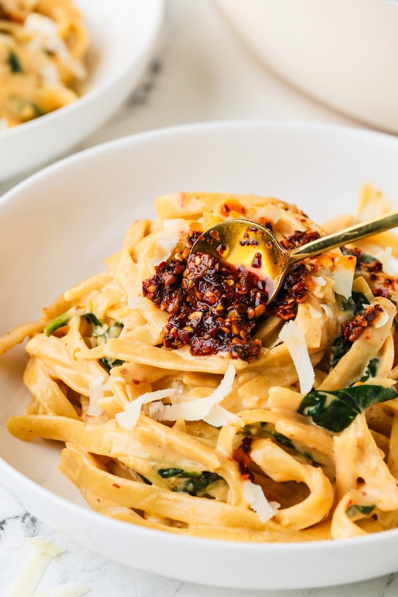 An close-up image of serving fettuccine alfredo on a plate.