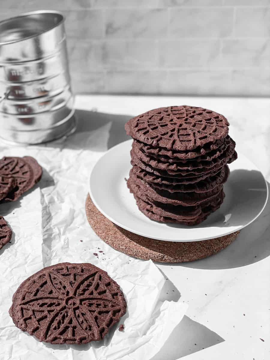 A straight shot of stacked chocolate pizzelle cookies.