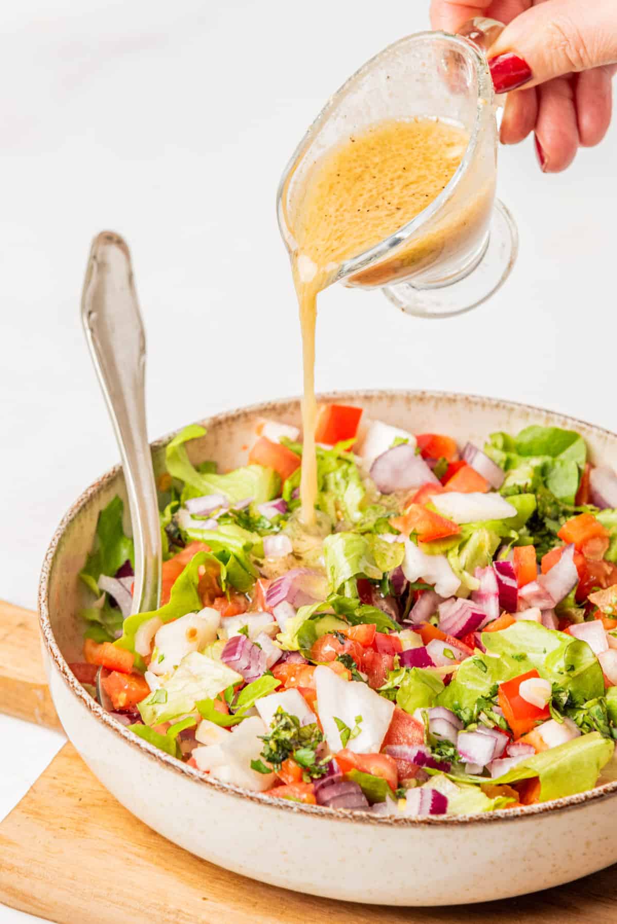 An image of chopped salad being drizzled with champagne vinaigrette