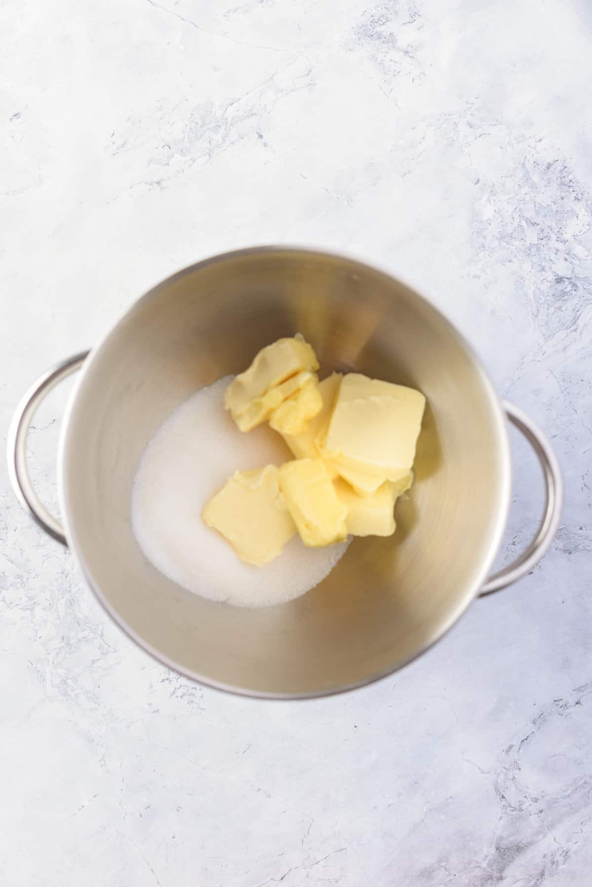Overhead view of butter and sugar in a large mixing bowl. 
