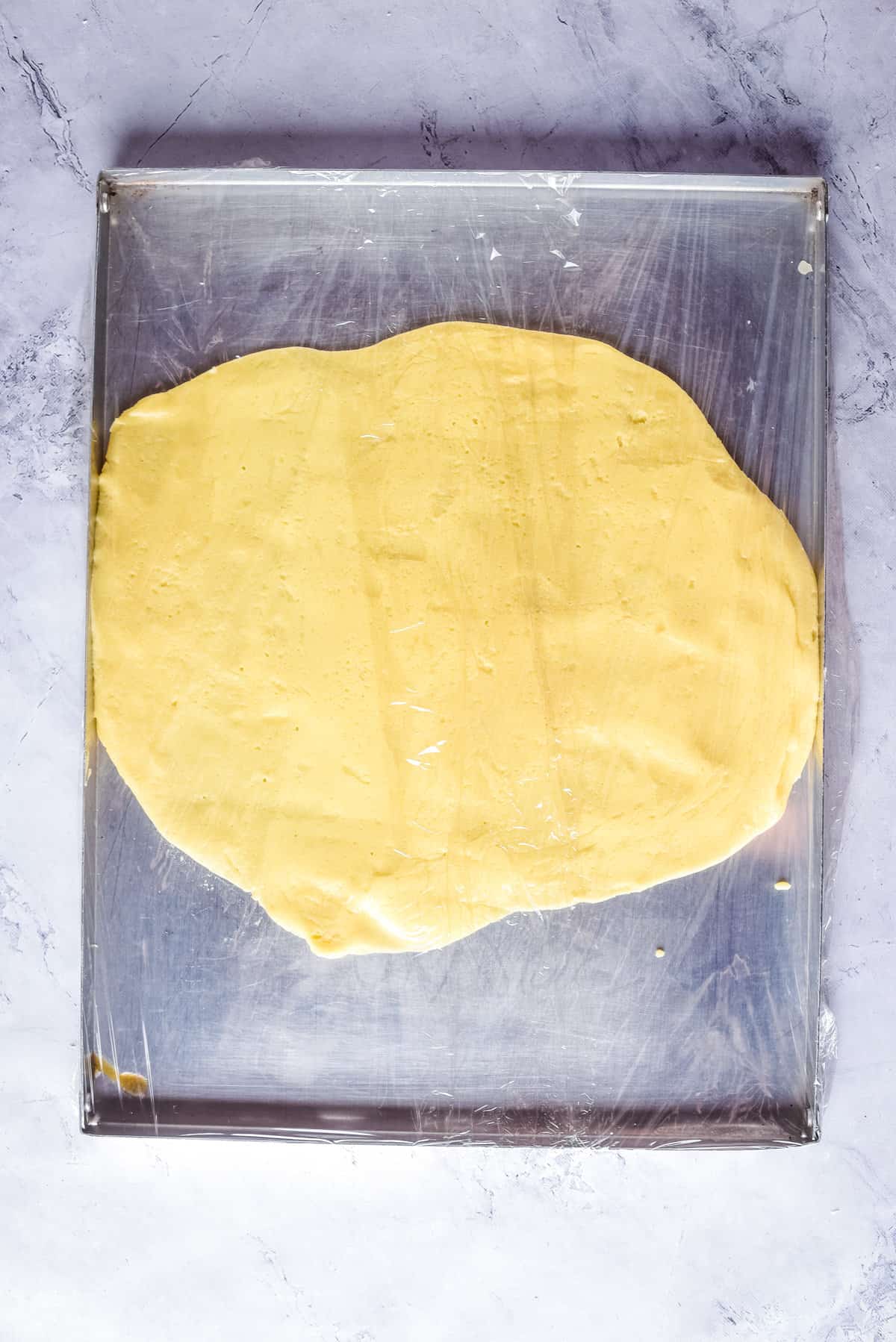Overhead view of dough on a flat surface, after being rolled out.
