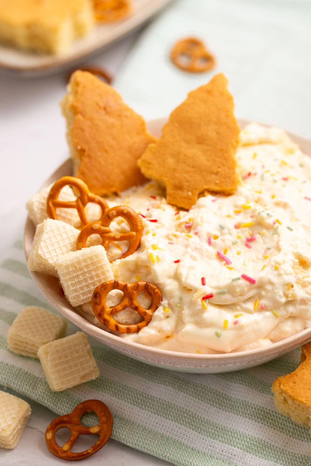 Homemade Christmas Tree Cake Dip topped with festive sprinkles and served with homemade tree-shaped cake pieces, vanilla wafers, and pretzels.