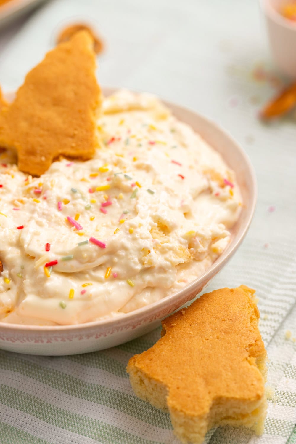 Finished homemade Christmas Tree Cake Dip topped with sprinkles and served with homemade cake pieces.