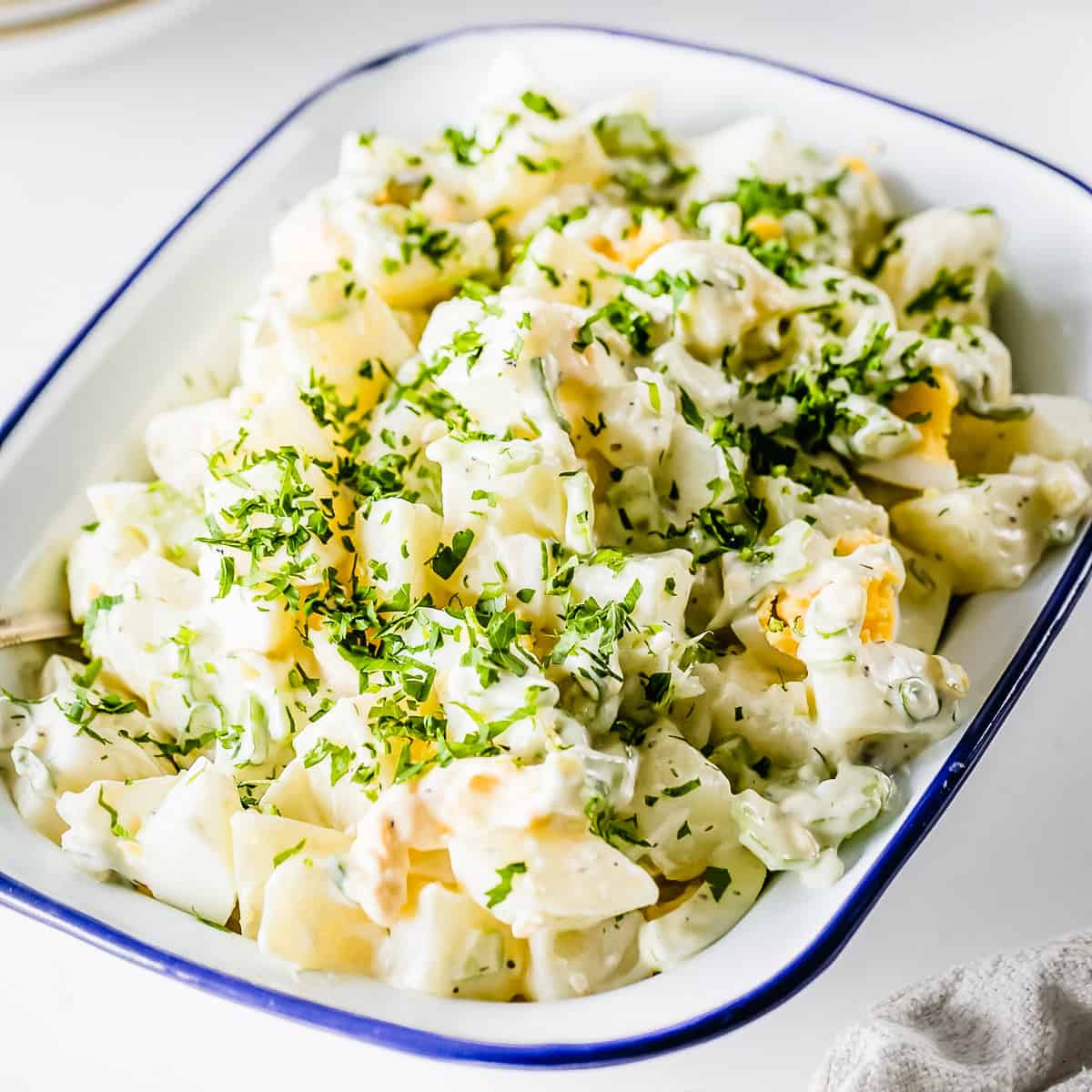 Side angle shot of classic potato salad in a white bowl. 