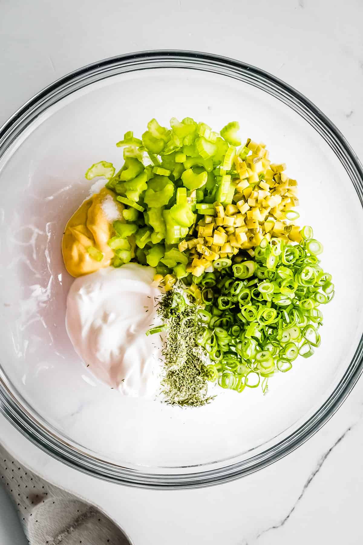 Overhead view of dressing ingredients in a large glass mixing bowl.