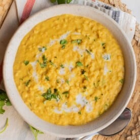 Overhead image of coconut red lentil curry served in a bowl over white rice.