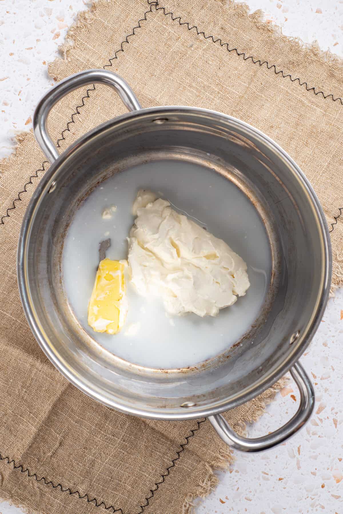 An image of butter and cream cheese being melted into a saucepan.