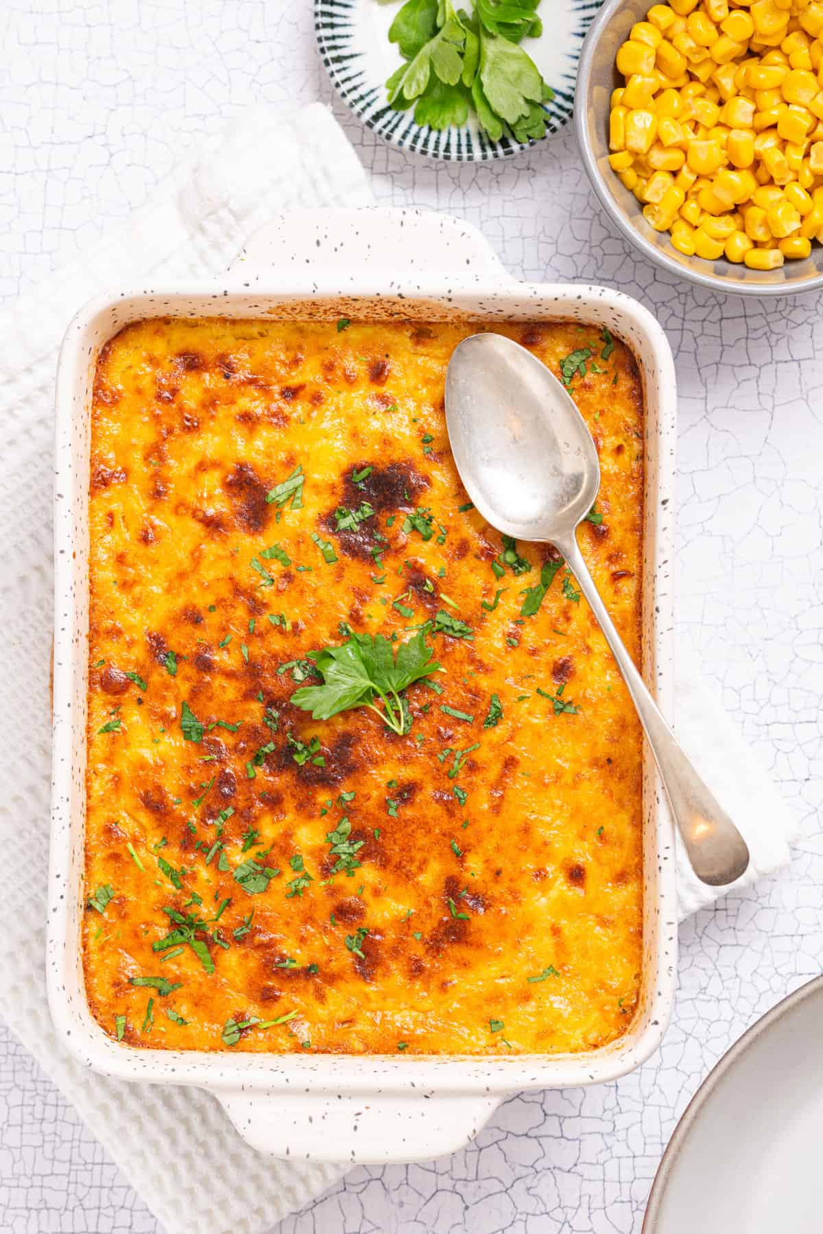 An overhead image of corn casserole with a spoon resting on top of it.