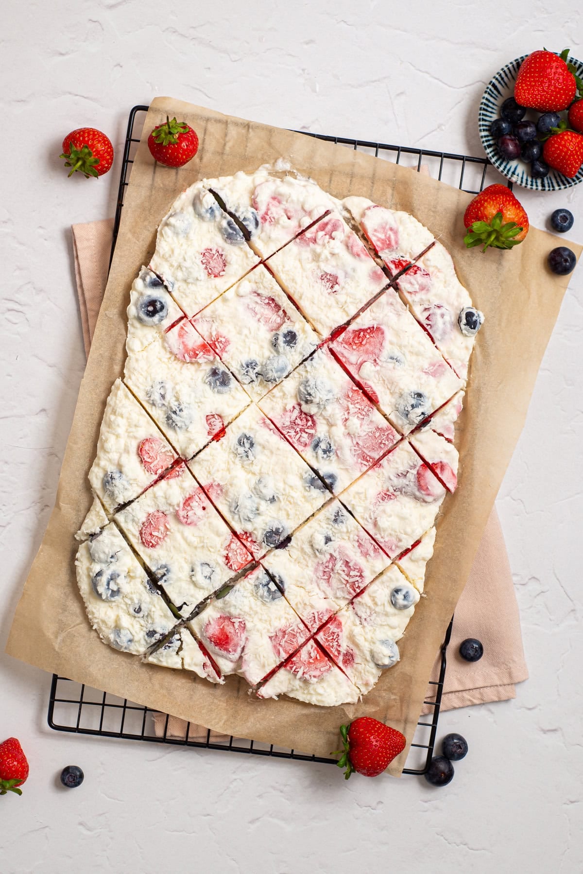 Frozen cottage cheese bark cut into squares on parchment paper over a cooling rack.