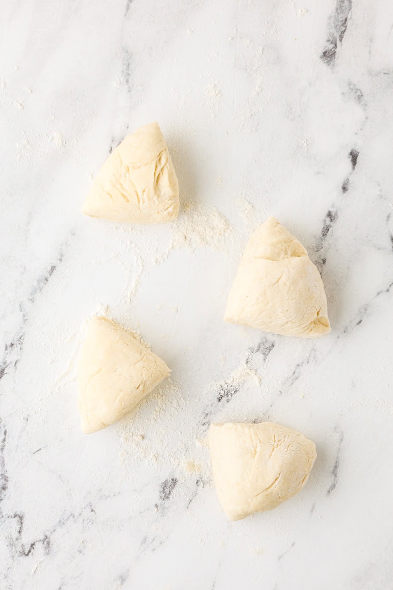 An overhead image of dividing the dough into four pieces.