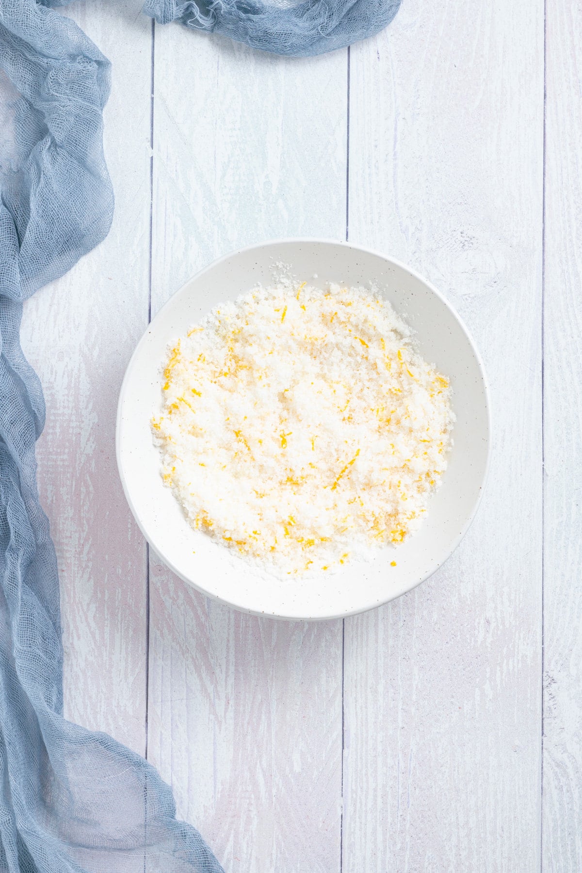 An overhead image of sugar and orange zest combined in a mixing bowl.