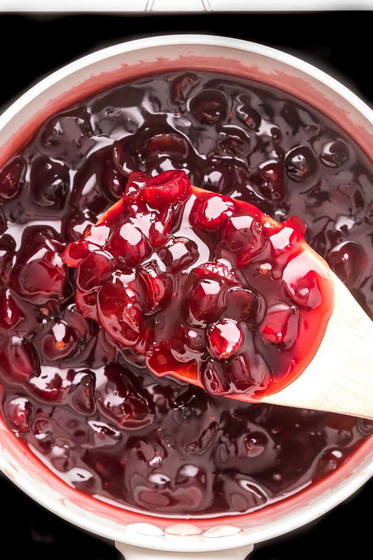 Overhead view of a spoonful of cranberry sauce in the pot.