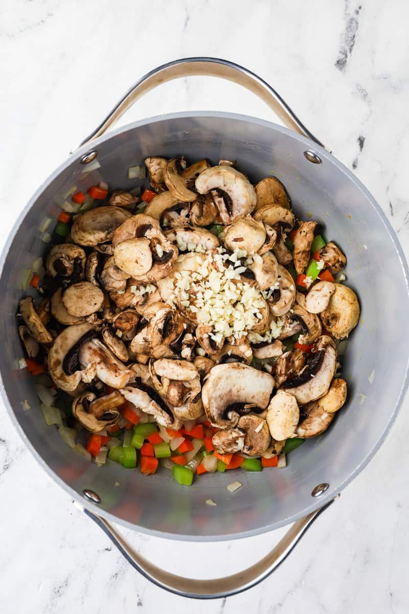 An overhead image of adding the mushrooms and garlic in a pot.