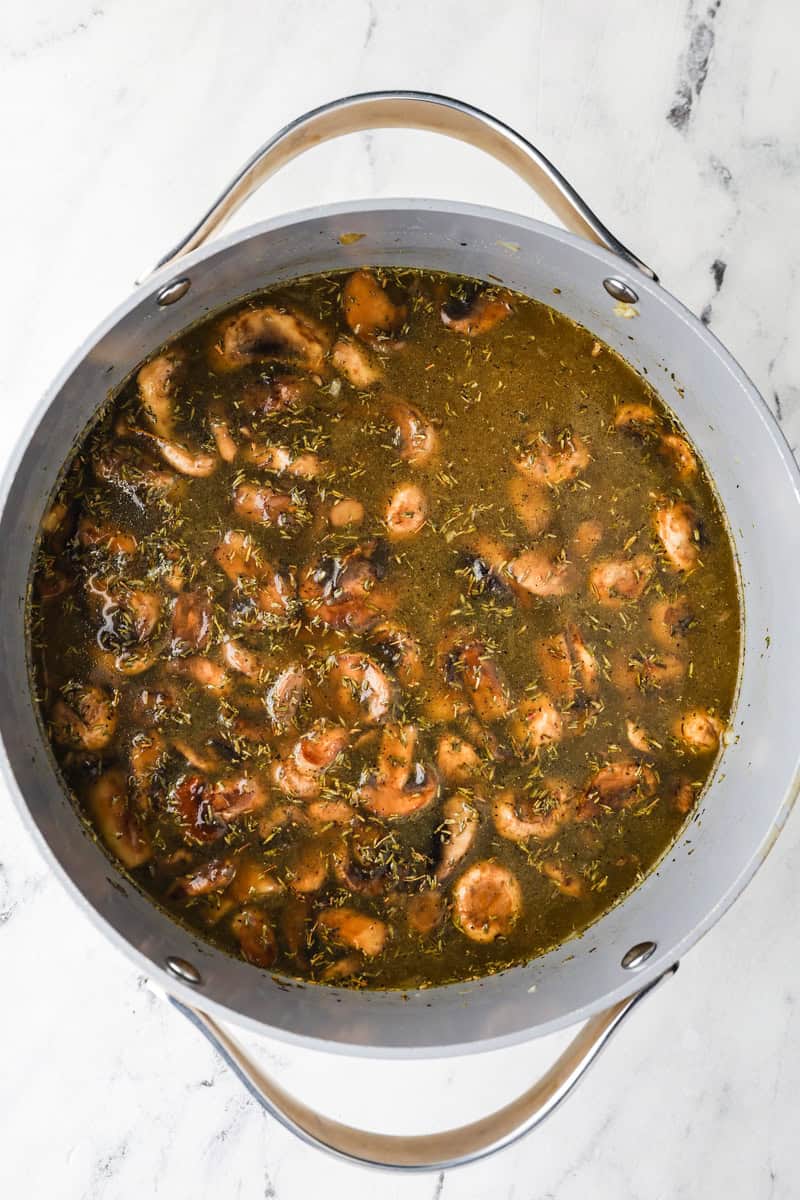An overhead image of adding the vegetable broth and seasonings.
