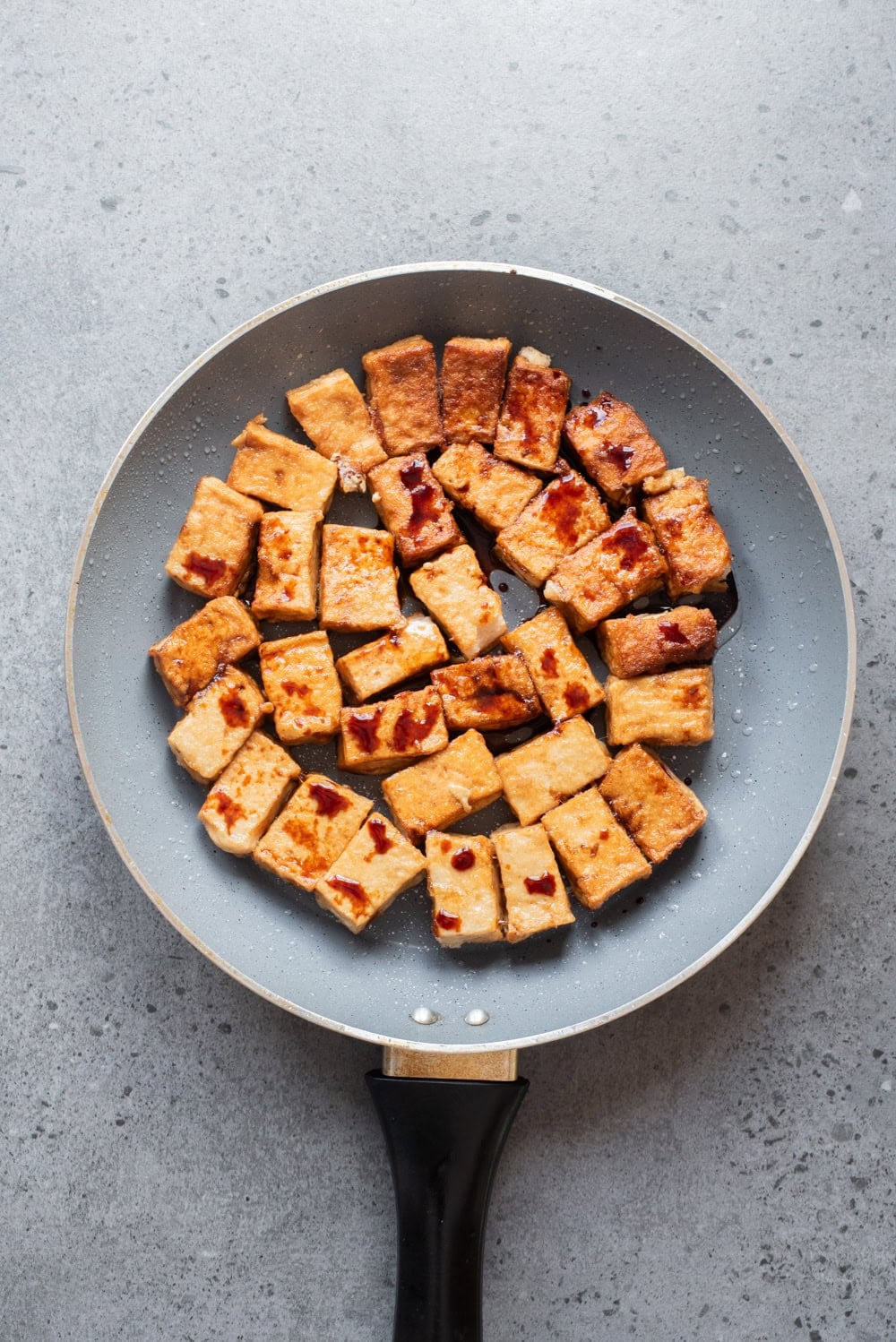 An overhead image of frying the tofu in a pan.