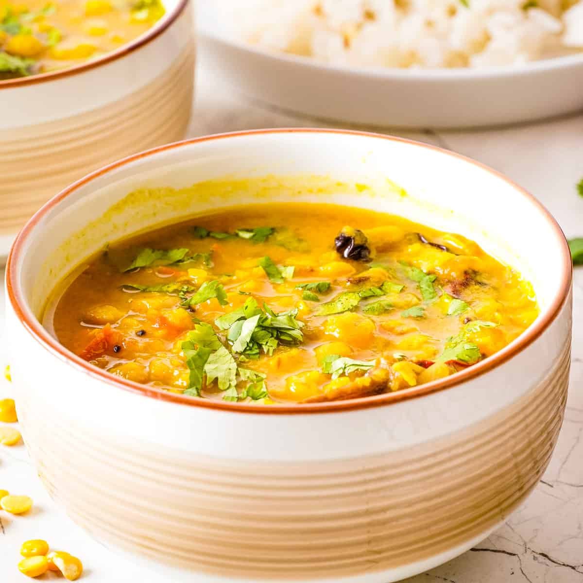 Close up view of dal tadka in a white bowl.