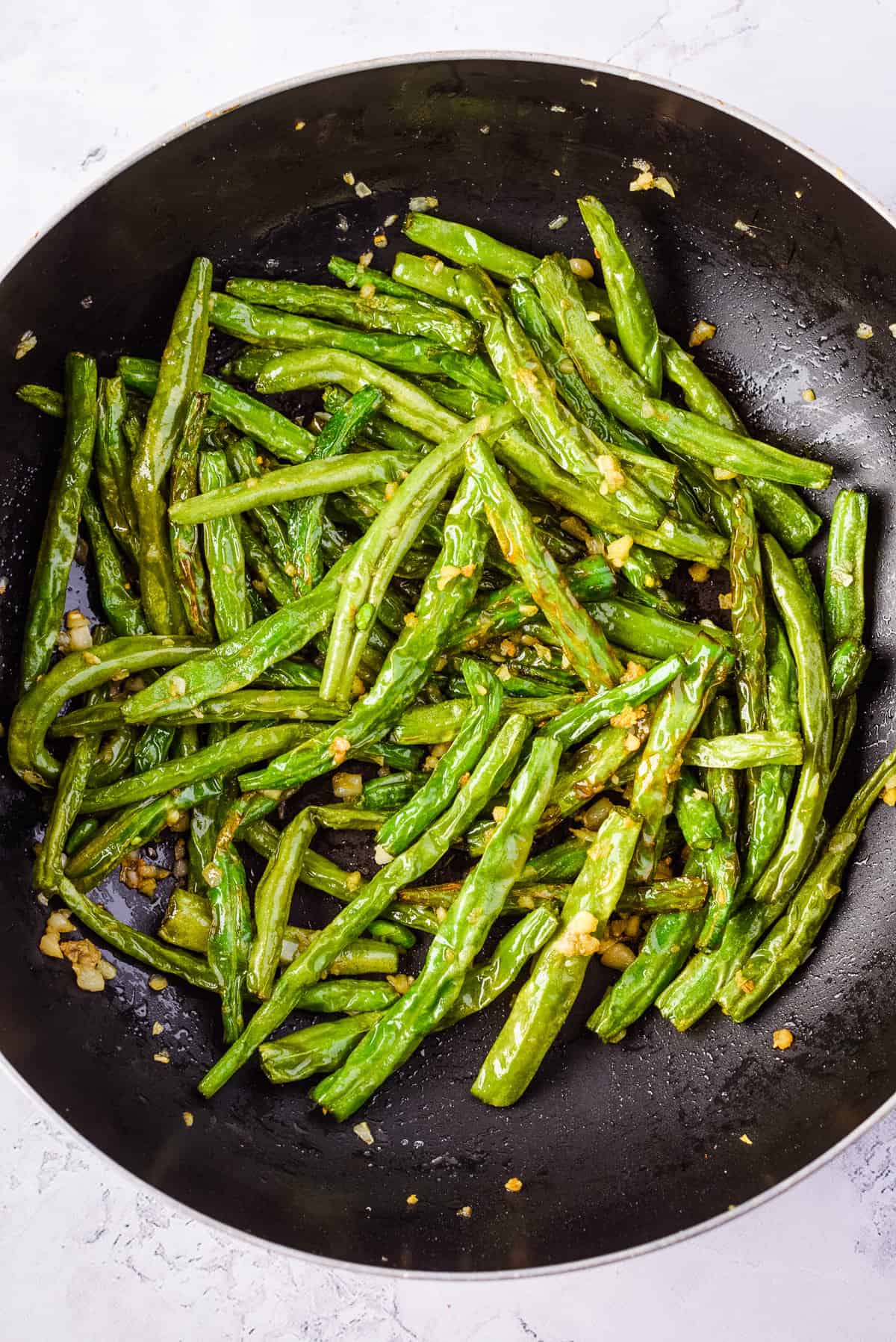 Close up of cooked Din Tai Fung green beans in black skillet.