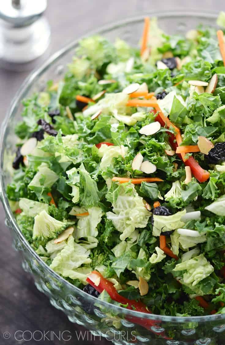 Close-up view of kale broccoli salad with citrus vinaigrette in a transparent bowl.