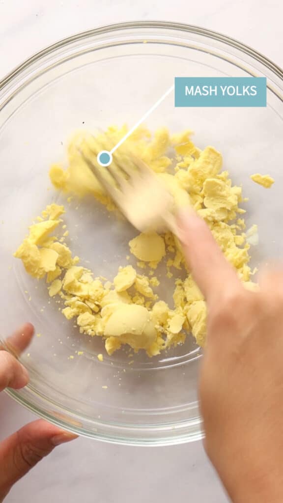 Mashing egg yolks with a gold fork.