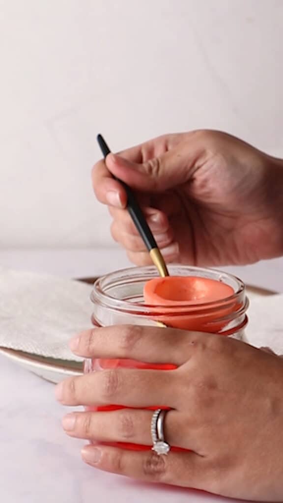 Removing red egg white halves from glass jar with a gold and black spoon.