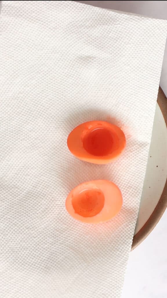 Red egg halves placed on a paper towel.