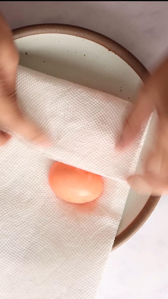 Pressing paper towel on egg halves to blot out excess water.