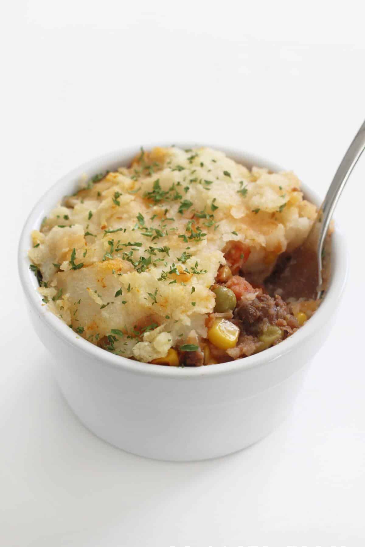 A close-up view of the easy lentil shepherd's pie placed on a white ramekin.