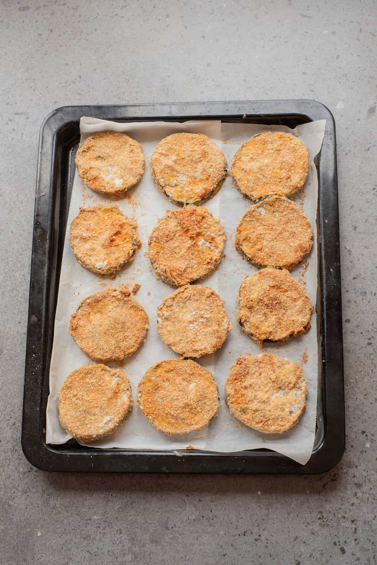 An overhead image of the eggplant slices arranged on a baking sheet.