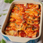 A close up image of eggplant rollatini in a baking dish.