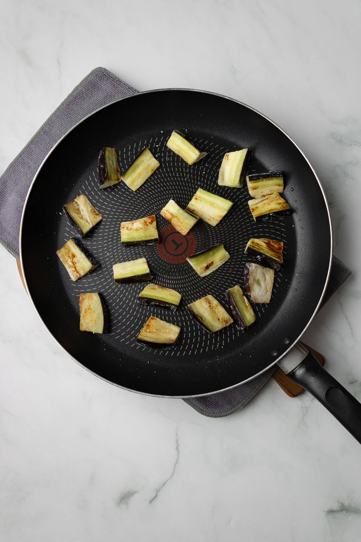An overhead image of frying eggplants on a skillet.